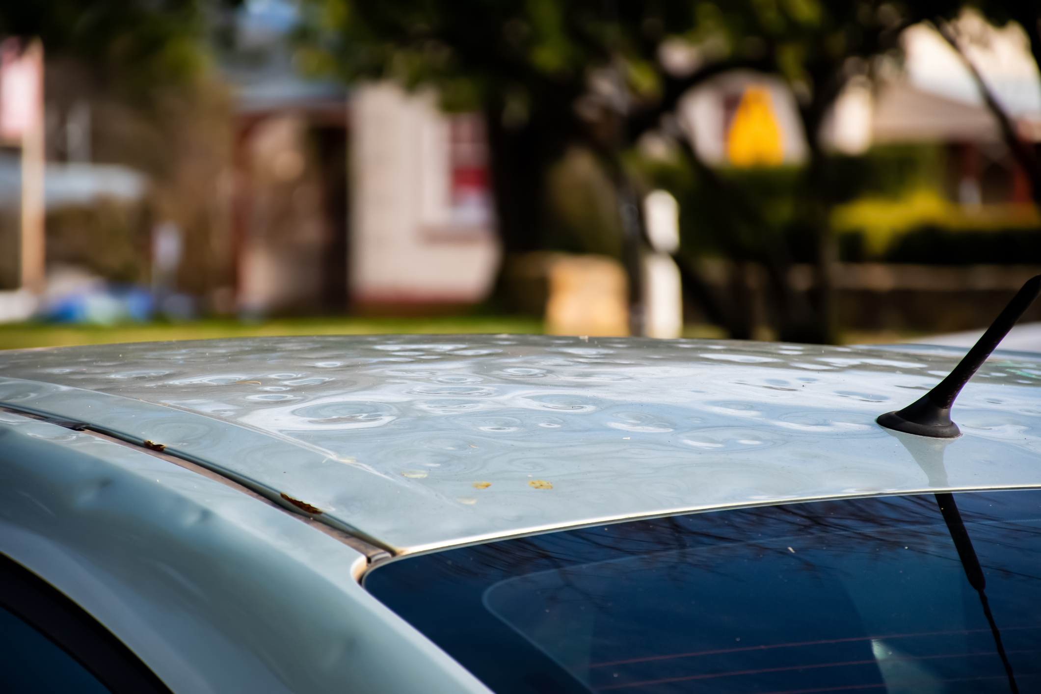 Car roof damaged by major hailstorm hailstones. Car insurance repair dents. Dented car rooftop